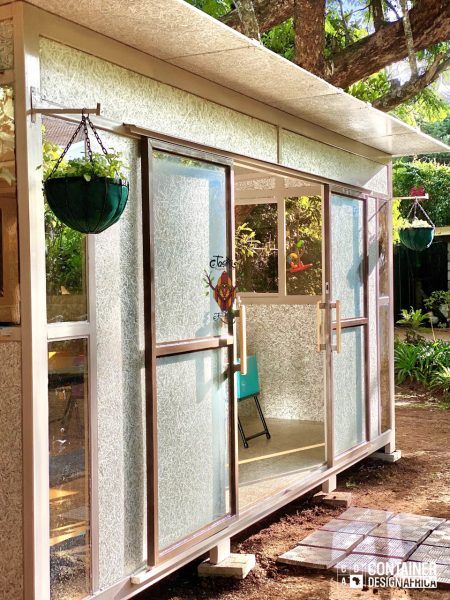 Modern sustainable classroom exterior with eco-friendly materials, large windows, and hanging garden planters