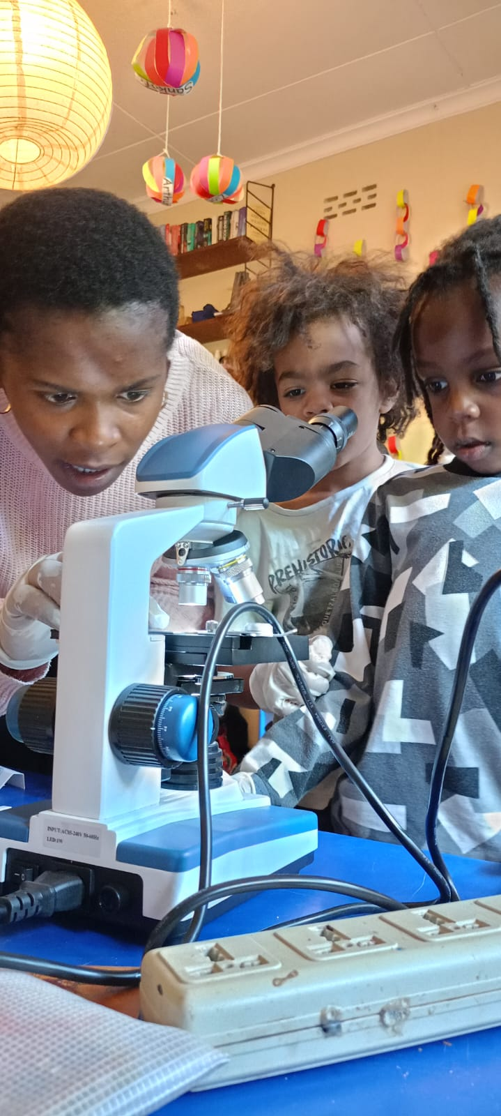 Students engaged in scientific inquiry and learning with a microscope